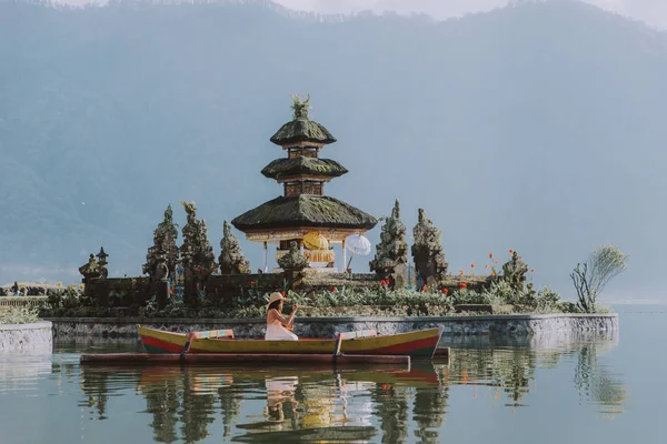 Ung kvinna Traveler paddling på en träbåt på Pura Ulun Danu — Stockfoto