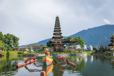 Pura Ulun Danu bir ahşap teknede genç kadın gezgin kürek çekmeye