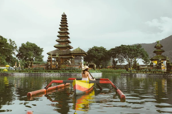 Ung kvinna Traveler paddling på en träbåt på Pura Ulun Danu — Stockfoto