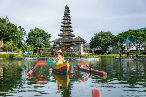 Ung kvinna Traveler paddling på en träbåt på Pura Ulun Danu — Stockfoto