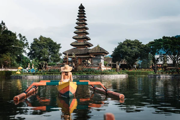 Ung kvinna Traveler paddling på en träbåt på Pura Ulun Danu — Stockfoto