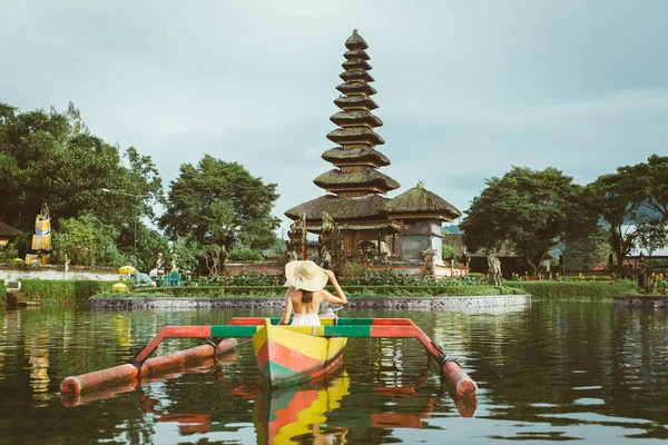 Ung kvinna Traveler paddling på en träbåt på Pura Ulun Danu — Stockfoto