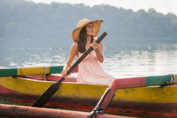 Junge Frau paddelt auf einem Holzboot bei pura ulun danu — Stockfoto