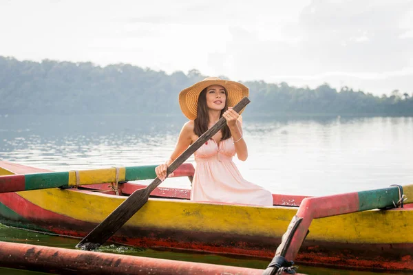 Junge Frau paddelt auf einem Holzboot bei pura ulun danu — Stockfoto