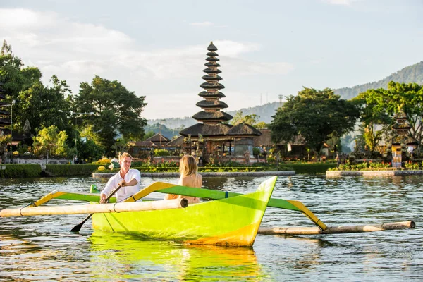 Ungt par paddling på en träbåt på Pura Ulun Danu BRATAN — Stockfoto