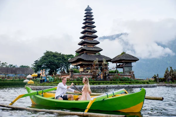 Ungt par paddling på en träbåt på Pura Ulun Danu BRATAN — Stockfoto