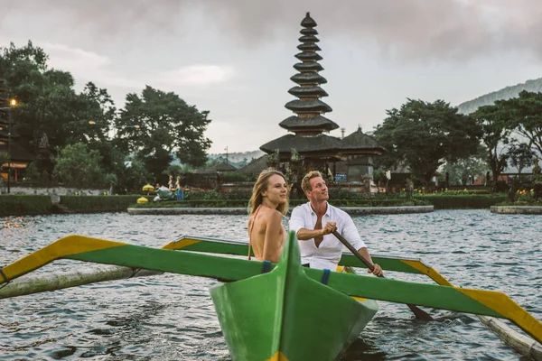 Junges Paar paddelt auf einem Holzboot bei pura ulun danu bratan — Stockfoto