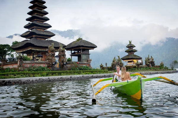 Young couple paddling on a wooden boat at Pura Ulun Danu Bratan — Stock Photo, Image