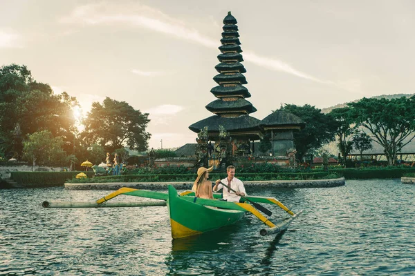 Ungt par paddling på en träbåt på Pura Ulun Danu BRATAN — Stockfoto