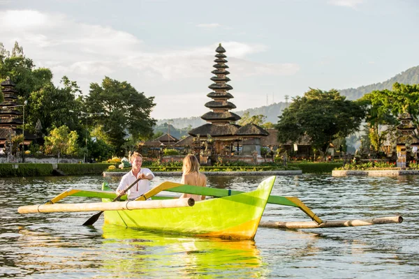 Ungt par paddling på en träbåt på Pura Ulun Danu BRATAN — Stockfoto