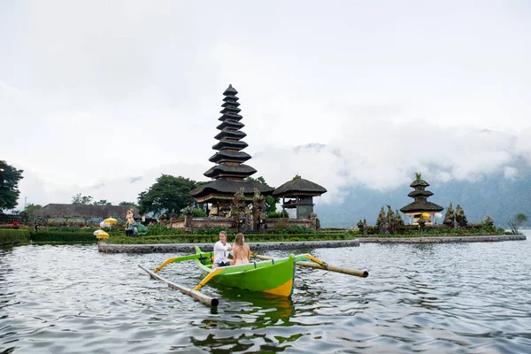 Ungt par paddling på en träbåt på Pura Ulun Danu BRATAN — Stockfoto