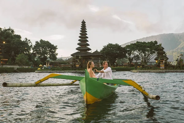 Ungt par paddling på en träbåt på Pura Ulun Danu BRATAN — Stockfoto