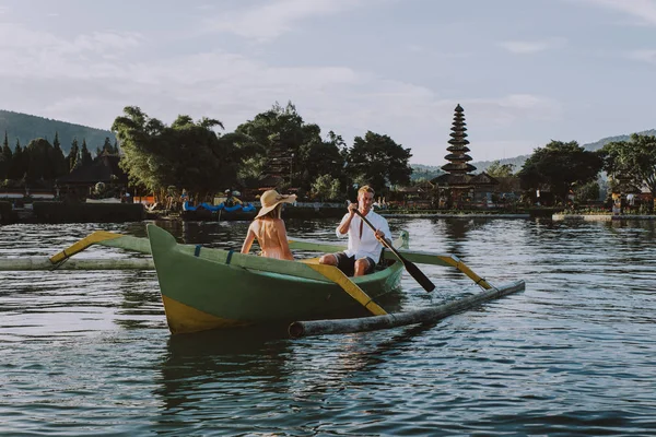 Junges Paar paddelt auf einem Holzboot bei pura ulun danu bratan — Stockfoto