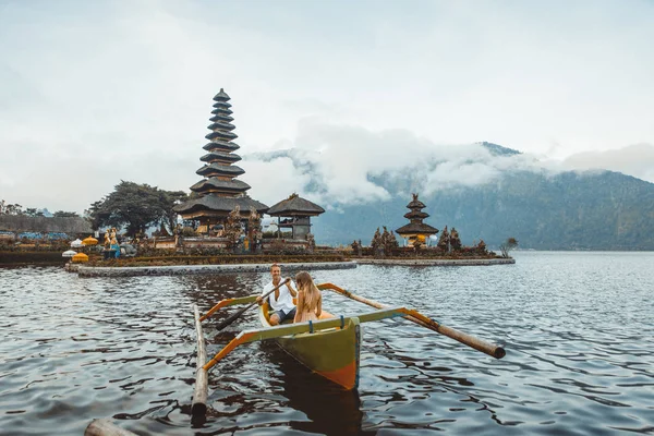 Ungt par paddling på en träbåt på Pura Ulun Danu BRATAN — Stockfoto