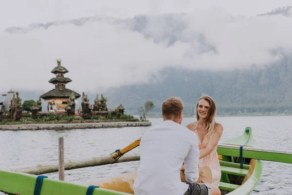 stock image Young couple paddling on a wooden boat at Pura Ulun Danu Bratan