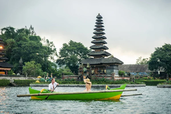 Pareja joven remando en un barco de madera en Pura Ulun Danu Bratan — Foto de Stock