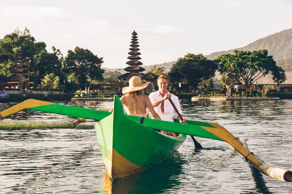 Junges Paar paddelt auf einem Holzboot bei pura ulun danu bratan — Stockfoto