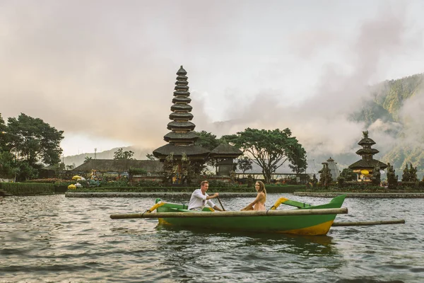 Ungt par paddling på en träbåt på Pura Ulun Danu BRATAN — Stockfoto