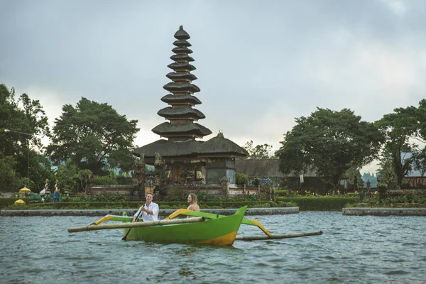 Ungt par paddling på en träbåt på Pura Ulun Danu BRATAN — Stockfoto