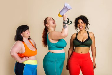 Stüdyoda spor kıyafetleri giyen iri yarı bir kadın vücut hatasını kabul eden güzel bir kız, stüdyoda güzel poziyonlar, vücut kabulü, pozitiflik ve çeşitlilik konseptleri.