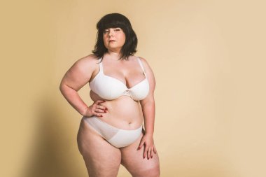 Stüdyoda poz veren iri yarı bir kadın, vücudunun kusurlarını kabul eden güzel bir kız, stüdyoda güzel bir poz, vücut kabulü, pozitiflik ve çeşitlilikle ilgili kavramlar.