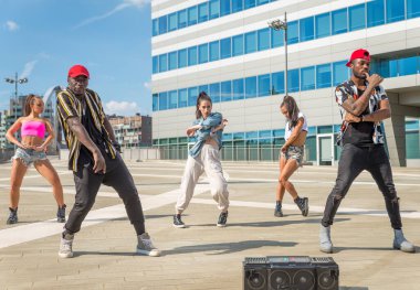 Hip hop ekibi dans ediyor, çok ırklı bir grup insan dışarıda eğleniyor.