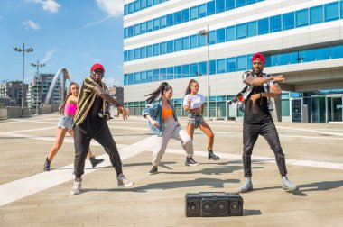 Hip hop ekibi dans ediyor, çok ırklı bir grup insan dışarıda eğleniyor.