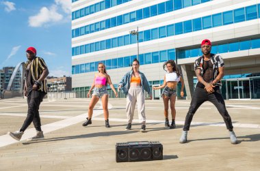 Hip hop ekibi dans ediyor, çok ırklı bir grup insan dışarıda eğleniyor.