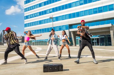 Hip hop ekibi dans ediyor, çok ırklı bir grup insan dışarıda eğleniyor.