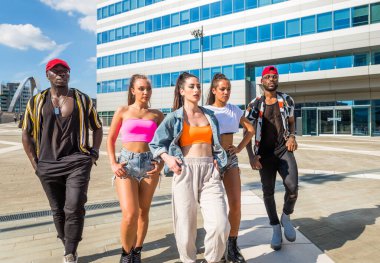 Hip hop ekibi dans ediyor, çok ırklı bir grup insan dışarıda eğleniyor.