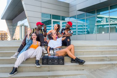 Hip hop ekibi dans ediyor, çok ırklı bir grup insan dışarıda eğleniyor.