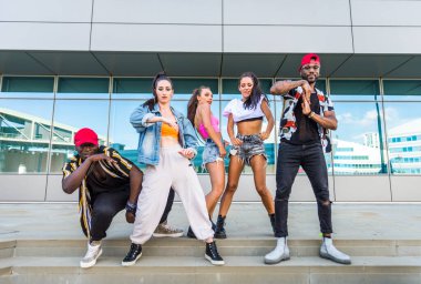 Hip hop ekibi dans ediyor, çok ırklı bir grup insan dışarıda eğleniyor.
