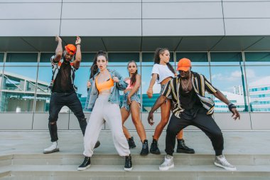 Hip hop ekibi dans ediyor, çok ırklı bir grup insan dışarıda eğleniyor.