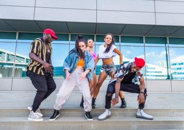 Hip hop ekibi dans ediyor, çok ırklı bir grup insan dışarıda eğleniyor.