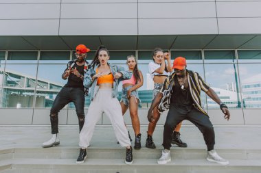Hip hop ekibi dans ediyor, çok ırklı bir grup insan dışarıda eğleniyor.