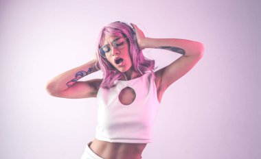 Pembe saçlı, dans eden ve eğlenen genç bir kadın. Fütürist kıyafetli renkli jel portreler.