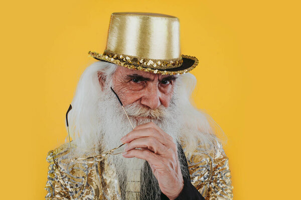 Fashionable grandfather posing with funny clothes. Senior man portraits on colored background