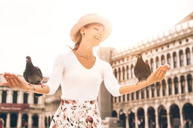 Venedik 'te güvercinlerle oynayan genç bir kadın. St. Mark Meydanı 'ndaki kuşları besleyen kız.