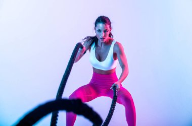 İple sıkı çalışan formda bir kadın. Spor salonunda egzersiz yapan bir kız. Vücut geliştirme ve yaşam tarzı kavramı