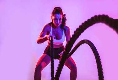 İple sıkı çalışan formda bir kadın. Spor salonunda egzersiz yapan bir kız. Vücut geliştirme ve yaşam tarzı kavramı