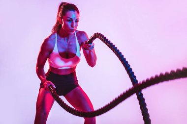 İple sıkı çalışan formda bir kadın. Spor salonunda egzersiz yapan bir kız. Vücut geliştirme ve yaşam tarzı kavramı