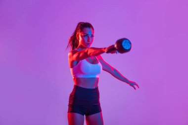 Spor kıyafetleri giymiş atletik bir kadın stüdyoda spor yapıyor.