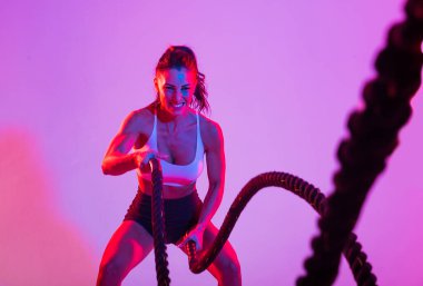 Spor kıyafetleri giymiş atletik bir kadın stüdyoda spor yapıyor.