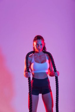 Spor kıyafetleri giymiş atletik bir kadın stüdyoda spor yapıyor.