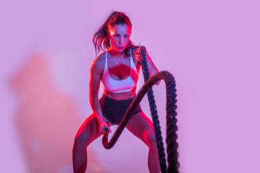 Spor kıyafetleri giymiş atletik bir kadın stüdyoda spor yapıyor.