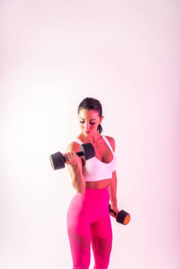 Spor kıyafetleri giymiş atletik bir kadın stüdyoda spor yapıyor.