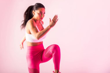 Spor kıyafetleri giymiş atletik bir kadın stüdyoda spor yapıyor.