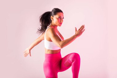 Spor kıyafetleri giymiş atletik bir kadın stüdyoda spor yapıyor.