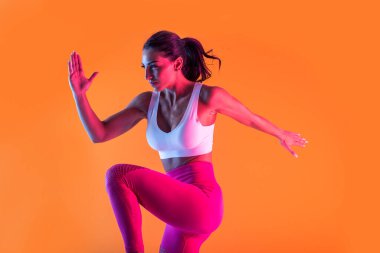 Spor kıyafetleri giymiş atletik bir kadın stüdyoda spor yapıyor.