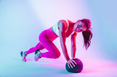 Spor kıyafetleri giymiş atletik bir kadın stüdyoda spor yapıyor.